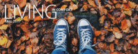 overhead shot of legs and feet in blue converse sneakers standing on wet autumn leaves